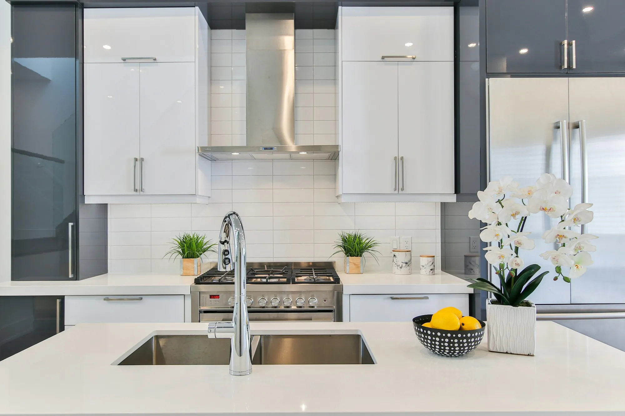 Modern white kitchen with a stainless steel faucet over a double sink
